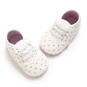 Detail of white infant sneakers with silver glitter hearts and soft pink-hearted soles.
