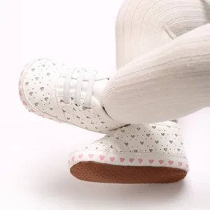 Close-up of baby soft-sole sneakers with silver heart pattern and pink hearts