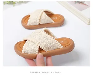 Primo piano di sandali per bambini in tessuto intrecciato crema e suola marrone.