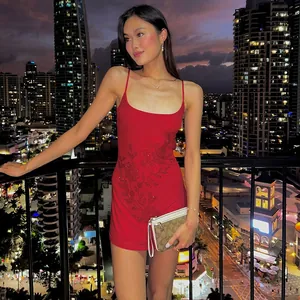 Detalle de vestido mini rojo con pedrería floral sobre un fondo urbano nocturno