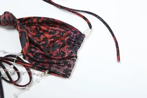 Detail view showing the bold leopard print and delicate pearl chain decoration on the dress.