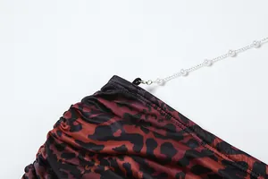 Detailed close-up of leopard print dress with an elegant white pearl chain decoration