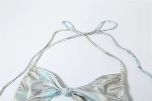 Detail view of halter dress featuring marble print and pearl chain strap accents.