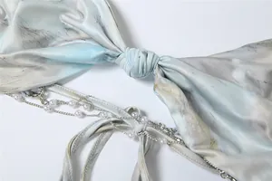 Macro detail of sexy halter neck dress featuring tie-up back and elegant pearl chain trim