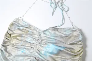 Close-up detail of pearl chain strap and marble print on light blue halter neck dress
