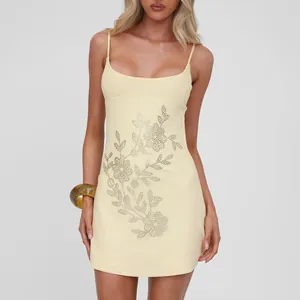 Detalle del elegante patrón floral de pedrería en el mini vestido amarillo.