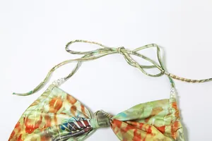 Detail view of halter dress with pearl bead accents and colorful abstract print straps.