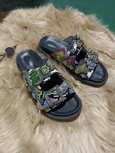 Detalle de sandalias de plataforma para mujer con piel de serpiente y tachuelas