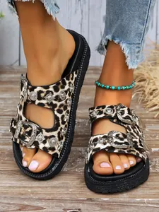 Detailed view of leopard print platform sandals with ornate silver metal buckles.
