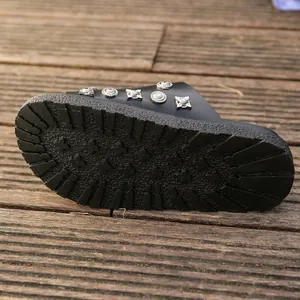 Close-up view of the durable non-slip platform sole and metal studs on black slide sandal