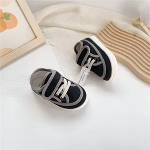 Detail view of black toddler canvas shoes with white soft soles and hook and loop closure.