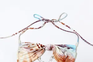Detail view of a sexy halter neck dress featuring pearl chain accents and abstract print.