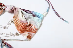 Close-up detail of a knot and pearl chain on a stylish tropical palm print halter dress