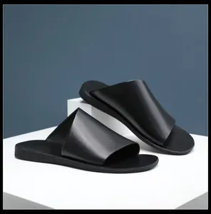 Primo piano di ciabatte in pelle nera premium da uomo su un supporto bianco.