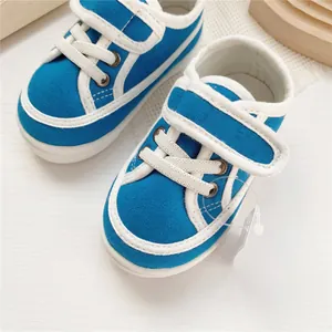 Close-up detail of blue baby canvas sneakers with soft white soles and velcro straps
