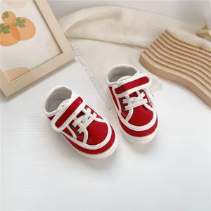 A top-down view of red baby canvas sneakers featuring soft soles and hook and loop straps
