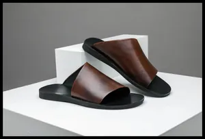 Dettaglio delle ciabatte da uomo in vera pelle marrone su un piedistallo bianco moderno