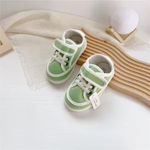 Close-up of green baby canvas shoes with velcro straps on decorative wooden background