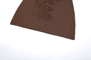 Primer plano del dobladillo de un vestido marrón con diseño floral de pedrería.