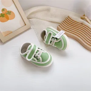 Overhead view of stylish green baby canvas sneakers featuring white soles and velcro straps
