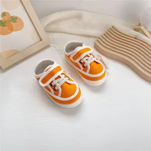 Close-up of bright orange baby canvas shoes with white Velcro straps and soft soles