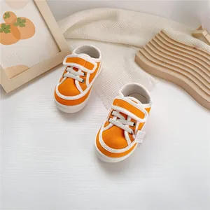 Vibrant orange kids canvas sneakers featuring Velcro straps and soft white soles