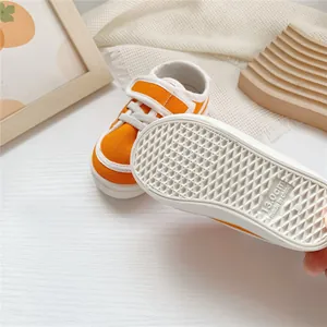 Detailed macro view of the anti-slip white rubber sole on orange children's canvas sneakers