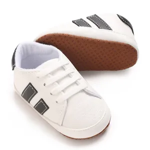 White baby sneakers for 0-18 months with soft brown anti-slip dot soles and black stripes
