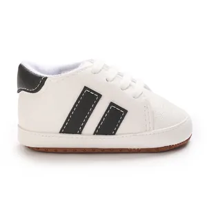 Close-up side view of white infant walking shoes with black stripes and comfortable soft soles
