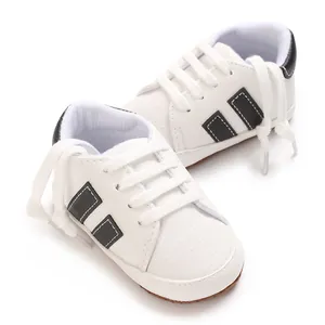 Detailed macro view of white infant walking sneakers with black stripes and soft soles.