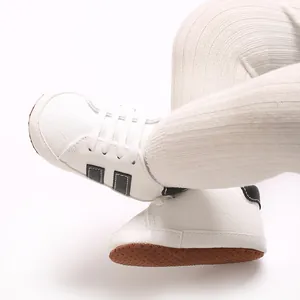 Detail of white baby pre-walker sneakers with soft non-slip soles and ribbed leggings