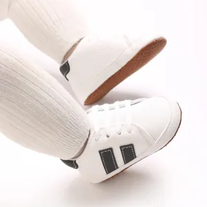 Detail view of white baby sneakers with anti-slip soft sole and sporty black accents.