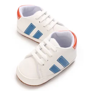 Detailed top-down view of white baby sneakers with blue stripes and orange heel accents