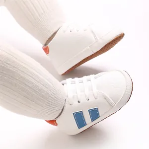 Close-up view of white infant walking shoes with blue stripes and soft non-slip soles