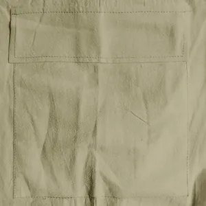 Close-up detail of a large cargo pocket on khaki linen shorts showing stitching