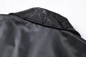 Macro detail of black satin suit vest lapel featuring intricate floral jacquard texture