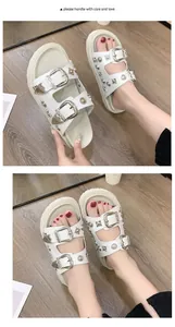 Primer plano de sandalias blancas con plataforma, hebillas de metal y tachuelas