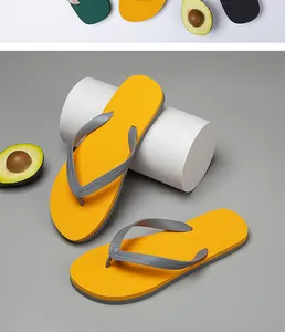 Primo piano di infradito da uomo gialle con cinturini grigi su sfondo grigio minimalista