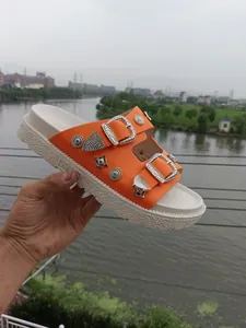 Detalle de sandalia de plataforma naranja con hebillas y tachuelas plata