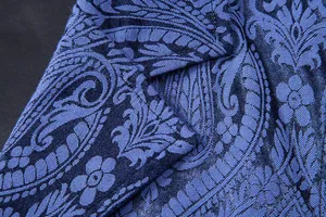 Detailed close-up of blue paisley jacquard fabric on a men's formal suit vest lapel
