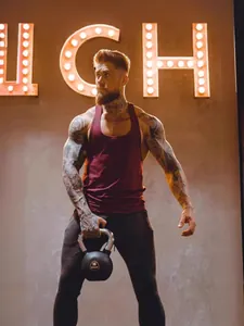 Débardeur de fitness bordeaux pour hommes, porté par un mannequin musclé en salle