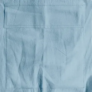 Close-up of linen fabric texture and cargo pocket stitching on light blue shorts