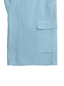 Close-up of light blue linen cargo shorts showing a large side flap pocket detail