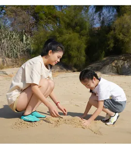 Parent et enfant en chaussures d'eau respirantes jouant sur une plage de sable ensoleillée