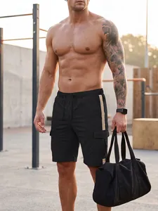 Full body view of men's black cargo shorts with beige side stripes in a gym setting