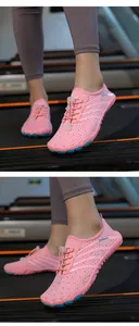 Close-up detail of pink breathable mesh water shoes with non-slip blue rubber soles on treadmill.