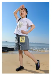 Enfant portant des chaussures d'eau noires respirantes sur une plage ensoleillée