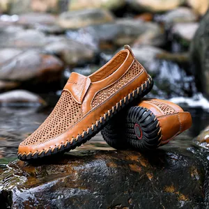 Detail van bruine herenloafers van leer met ademend mesh op natte rivierstenen in de natuur