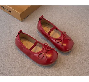 Zapatos Mary Jane rojos para niña con lazo y correa elástica en una vista de detalle superior.