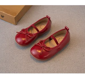 Detalle de zapatos Mary Jane rojos en cuero brillante para niñas con lazo decoro